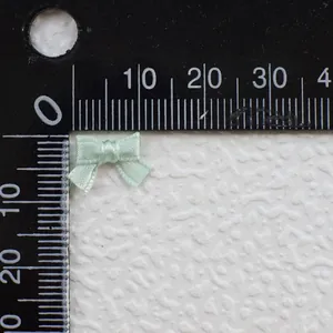 Macro detail of 15mm mint green satin ribbon bow for BJD doll clothes with ruler scale