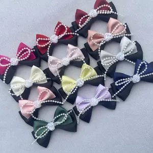Detalle de lazos de satén hechos a mano con rosas en relieve y cadenas de perlas falsas