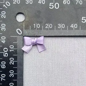 Vista dettagliata di un fiocco in raso viola da 20mm misurato con un righello per il fai-da-te