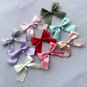 Flat lay of colorful 7.5cm satin bow accessories for hair and clothing in nine shades
