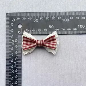 Detail of red gingham bow with white lace trim showing size measurements via ruler