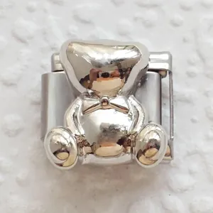 Macro view of modular 3D teddy bear charm in polished silver metal with bow detail