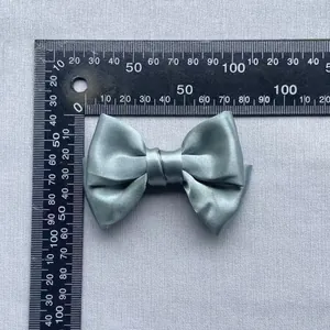 Detailed size measurement of a 85mm sage green satin ribbon bow accessory with a ruler