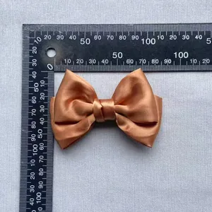 Detail of a bronze satin bow accessory showing fabric texture and 85mm size measurements