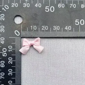 Dettaglio di un fiocco rosa in poliestere da 1,5 cm misurato su una scala graduata
