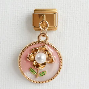 Makro-Detail des italienischen Charm-Armbands mit Goldblume, Perle und rosa Emaille