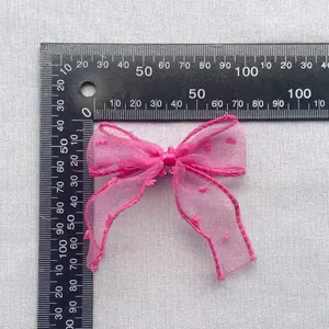 Détail du nœud en tulle rose à pois floqués avec une règle indiquant les dimensions
