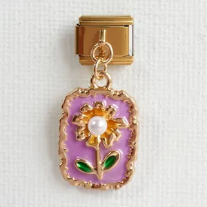 Nahaufnahme eines italienischen Charms mit goldener Blume und Perle auf lila Emaille-Hintergrund