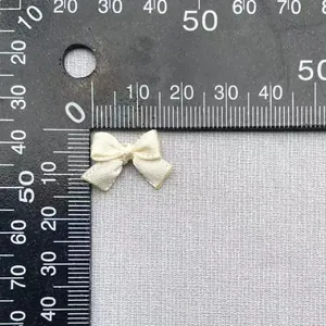 Dettaglio di un fiocco in raso crema da 1,5 cm misurato con righello per progetti DIY