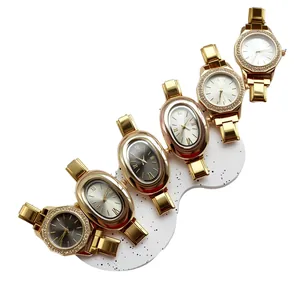 Eleganti orologi al quarzo dorati con casse esagonali e ovali su espositori bianchi