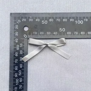 Makroaufnahme einer 40 mm silbernen Satinschleife mit Lineal zur Größenbestimmung