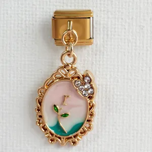 Makroaufnahme des vergoldeten Charms mit Emaille-Blumenmuster und funkelnden Strasssteinen