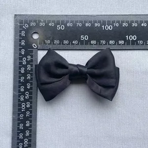 Detail view of a 9.5cm black satin bow accessory with ruler showing precise dimensions