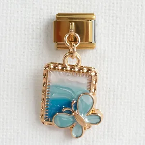 Detail eines italienischen Charm-Armbands mit Goldrahmen und blauem Emaille-Schmetterling
