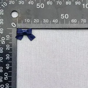 Dettaglio macro di un fiocco in raso blu navy da 1,5 cm su un righello di misura