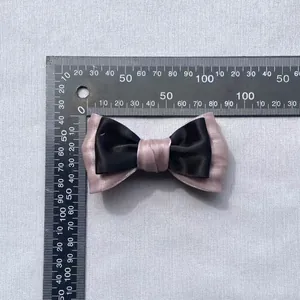 Detail view of a 9.5cm two-tone layered satin bow showing size measurements on a ruler
