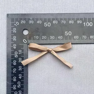 Detailansicht einer 45mm champagnergoldenen Satinschleife mit Lineal zur Messung
