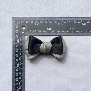Detail of a double-layered Morandi bow accessory showing 8.5cm measurement on a scale