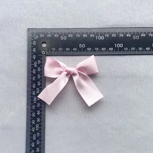 Detailed view of a 7.5cm pink satin ribbon bow with measuring ruler for accessory sizing