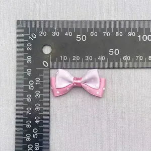 Macro detail of a 3.5cm double-layer pink and purple polka dot ribbon bow with ruler