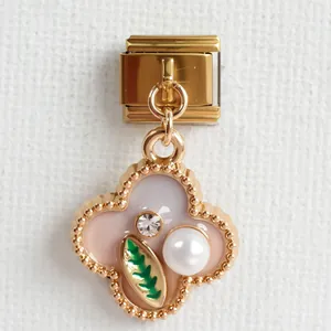 Detail eines Kleeblatt-Charms mit Perle und Kristall auf rosa Emaille-Hintergrund