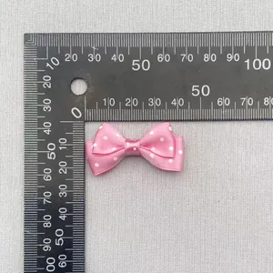 Detail view of a 40mm pink polka dot ribbon bow with measurement ruler for scale