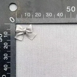 Misurazione dettagliata di un fiocco di raso grigio da 2 cm con righello per fai da te