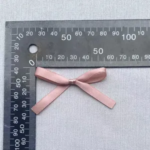 Makroansicht einer hellrosa Satinschleife von 45 mm Breite mit einem Lineal