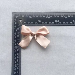 Detailed top view of a 7.5cm champagne satin ribbon bow accessory for garment decor