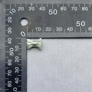 Primer plano de un lazo de doble capa verde claro de 15 mm sobre una regla métrica