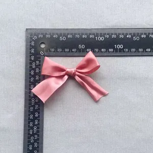Close-up of a pink satin ribbon bow accessory with ruler for 7.5cm size reference