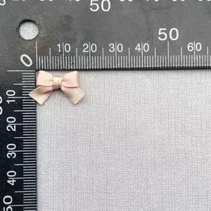 Macro di un fiocco in poliestere rosa chiaro da 1,5cm fatto a mano con scala graduata