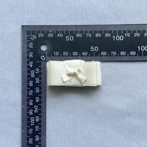 Detailopname van handgemaakte crèmewitte kanten strik accessoire met afmetingen