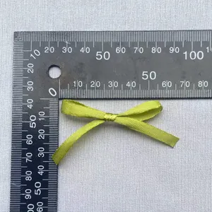 Detail eines avocadogrünen Satinbandschleifen-Zubehörs mit präzisen Maßen auf der Skala
