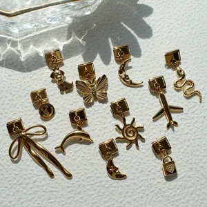 Detalle de dijes italianos dorados con diseños de cachorros, delfines y motivos celestes