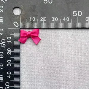 Dettaglio fiocco in raso rosa con righello che mostra la larghezza di 22mm
