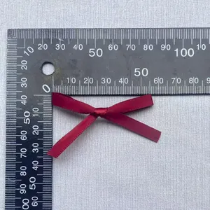Detail einer 50mm weinroten Satinschleife mit seidiger Textur und Größenmaß auf Lineal