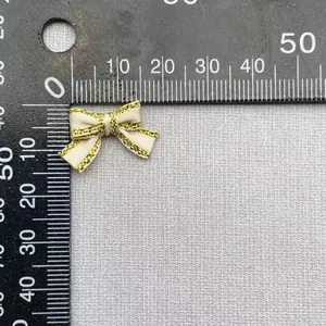 Dettaglio di un fiocco di raso crema da 2,5 cm con bordi glitterati oro e righello