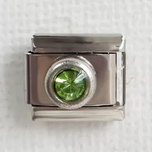 Macro detail of Italian charm link in silver stainless steel with faceted green gemstone