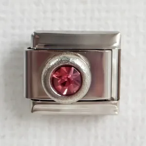 Macro detail of Italian charm link in stainless steel with a round pink birthstone crystal