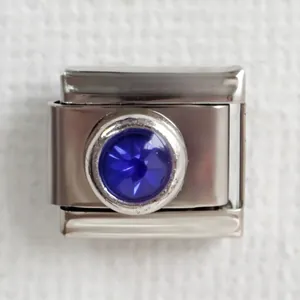 Macro shot of stainless steel Italian charm with round faceted deep blue gemstone inlay