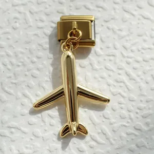 Detalle de un colgante de avión dorado en un eslabón de pulsera modular italiana