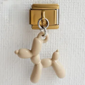 Dettaglio di un ciondolo a forma di cane palloncino crema su una maglia d'oro italiana