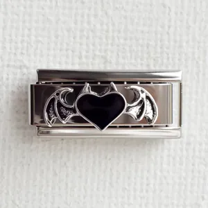 Détail d'un charme modulaire argenté avec cœur noir et ailes de chauve-souris scintillantes
