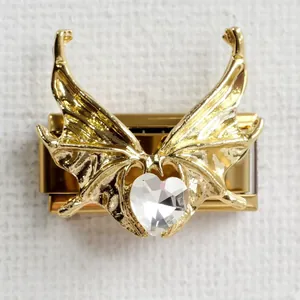 Macro detail of Italian charm bracelet link with gold butterfly wings and heart crystal