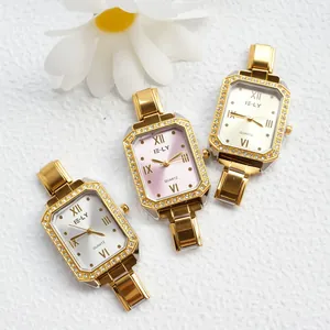 Dettaglio di tre orologi al quarzo quadrati dorati con lunette incastonate di cristalli