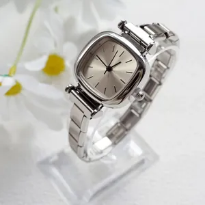 Gros plan d'une montre femme carrée en argent avec bracelet à maillons en acier