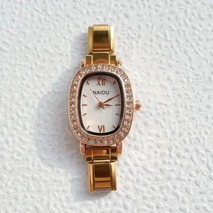 Detail van gouden quartzhorloge met kristallen ovale wijzerplaat en metalen schakelband