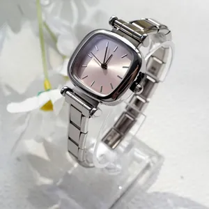 Détail macro d'une montre carrée argentée avec cadran rose soleil et bracelet en métal