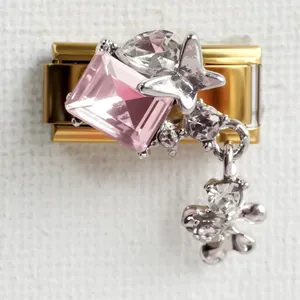 Macro shot of Italian charm link featuring a pink square gem, butterfly, and bear charm